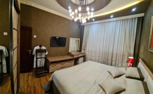 a bedroom with a bed and a television and a chandelier at LUXURIOUS ACCOMMODATION IN 2BR APARTMENT, IN A SECURED AREA WITH COMFORTABLE DISTANCE TO R/W STATION, AIRPORT AND CITY CENTER. in Tashkent +5 photos