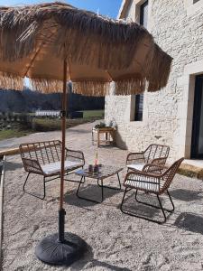 un patio con 2 sillas y una mesa con sombrilla en P'tit cocon au cœur du Lot, en Dégagnac