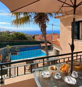 a table with a bowl of fruit on a balcony at Villa Oleander Madeira - Sunny - Ocean View - Heated Pool in Tábua