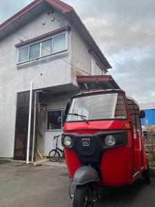 un pequeño vehículo rojo estacionado frente a un edificio en guest house goose - Vacation STAY 23621v, en Hirosaki