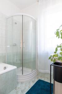a glass shower in a bathroom with a tub at AKÁCIA APARTMAN in Nyíregyháza