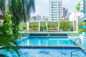 una piscina en la azotea de un edificio con palmeras en Country International Hotel, en Barranquilla