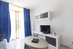 ein weißes Wohnzimmer mit einem TV und einem Tisch in der Unterkunft Complejo Residencial-CAT-8 in Salou