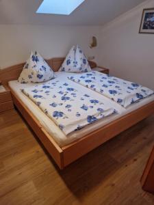 a bed with a blue and white comforter and pillows at Landhaus Salzmann in Bad Hofgastein