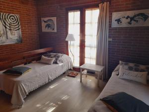 1 dormitorio con 2 camas y pared de ladrillo en La Maga, Casa para Familias en Pinamar