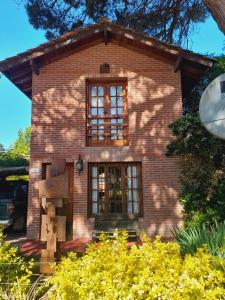 ein Backsteinhaus mit einem Fenster und einigen Büschen in der Unterkunft La Maga, Casa para Familias in Pinamar