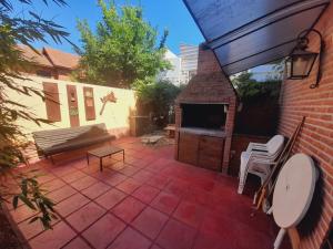 eine Außenterrasse mit einer Bank und einem Kamin in der Unterkunft La Maga, Casa para Familias in Pinamar + 5 Fotos