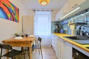 a kitchen with a wooden table and chairs and a sink at Apartament Pod Jałowcem Góry Sowie 533-543-732 in Jedlina-Zdrój