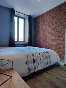 1 dormitorio con cama y pared de ladrillo en Les Studios De Flo' : The Bel'Factory 38 m² WIFI en Belfort