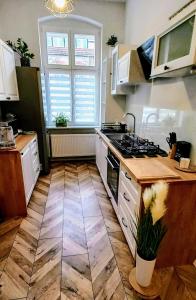 a kitchen with white cabinets and a wooden floor at Apartament Mickiewicz - Center in Słupsk