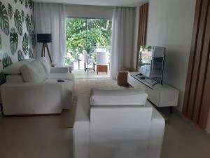 a living room with white furniture and a large window at Apartamento pé na areia in Porto Seguro