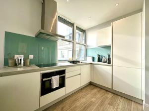 una cucina con armadi verdi e bianchi e una finestra di Stylish 2 Bedroom Apartment - Free Parking & WiFi - 1 Minute walk to Poole Quay - Great Location - Free Parking - Fast WiFi - Smart TV - Newly decorated - sleeps up to 4! Close to Poole & Bournemouth & Sandbanks a Poole