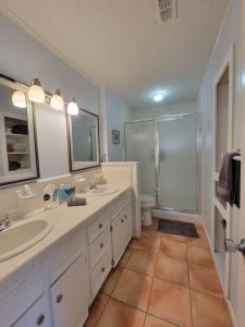 a white bathroom with two sinks and a shower at Paradise lagoon*bayhouse fishing*beach*Dogfriendly in Galveston