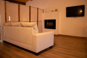 ein weißes Sofa im Wohnzimmer mit einem Flachbild-TV in der Unterkunft MonResidence La Figuereta in Manresa