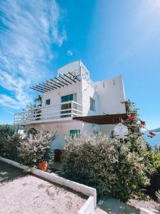 a white house with a balcony on the beach at Casa Mar da Grécia in Arraial do Cabo