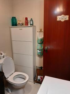 uma casa de banho com um WC branco e uma porta vermelha em Almadense em Almada