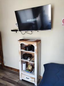 a flat screen tv on a wall above a wooden book shelf at Casita de Piedra 10 in Trinidad
