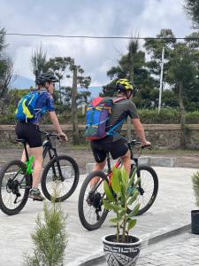 duas pessoas em bicicletas com mochilas e uma planta em Cahyo Homestay Bromo em Bromo