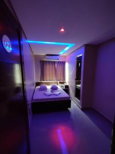 a room with a bed with purple lights on it at Hotel Simba in São Bernardo do Campo