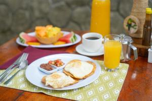 a table with plates of breakfast food and orange juice at Tree Houses Hotel Costa Rica in Florencia