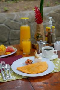 a table with a plate of breakfast food and orange juice at Tree Houses Hotel Costa Rica in Florencia