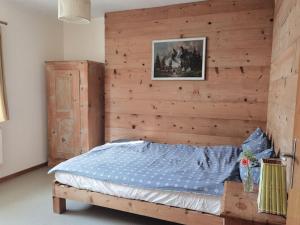 a bed in a room with a wooden wall at 1 Bedroom Apartment in Capolago in Maloja