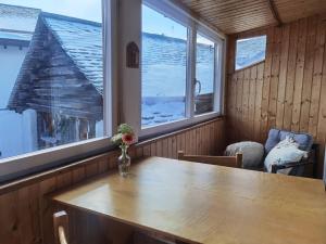 a room with a wooden table and two windows at 1 Bedroom Apartment in Capolago in Maloja