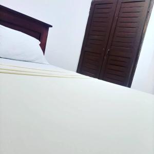 a bed with white sheets and a brown door at Résidence Sainte Honorine in Yaoundé