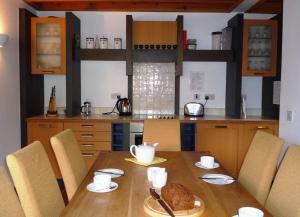 una cucina con tavolo in legno, sedie e un angolo cottura. di Waterville Holiday Homes No 10 a Waterville