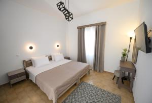 a bedroom with a large white bed and a desk at Verano Apartments in Kalymnos