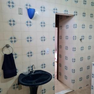 a bathroom with a black sink and blue and white tiles at Casarão Hostel Peró in Cabo Frio