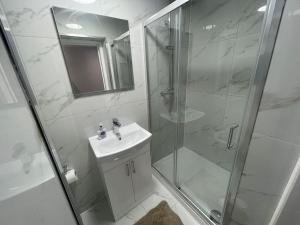 La salle de bains blanche est pourvue d'une douche et d'un lavabo. dans l'établissement Good priced 6 Bedroom Home with FREE Parking Family Holiday - Windsor, à Old Windsor