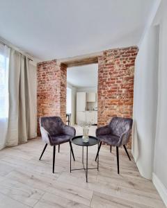 - 2 chaises et une table dans une chambre dotée d'un mur en briques dans l'établissement Võru apartment 4, free parking, à Tartu