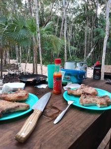 una mesa de madera con dos platos de comida. en Zil-Kaab Hidden Glamping Village, en Tulum