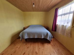 a bedroom with a bed in a room with a window at Cabañas Isabella in Chonchi