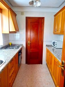 uma cozinha com armários de madeira e uma porta vermelha em El Mirador em Higuera de la Sierra