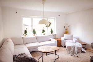 a living room with a white couch and two chairs at Gemütliches Haus mit Holzofen & Garten in Landshut
