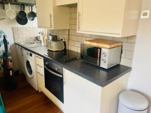 une cuisine avec un comptoir avec un grille-pain et un micro-ondes dans l'établissement Sun Street Cottage - with log burner, jet bath and Summerhouse, à Haworth