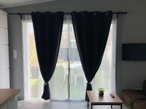 a large window with black curtains in a living room at T3 indépendant avec jardin in Saint Malo