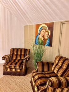 a living room with two chairs and a painting at Foresteria Santa Maria di Betlem in Foligno