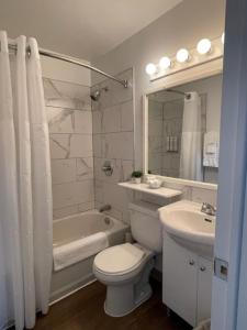 a white bathroom with a toilet and a sink at Hôtel Les Mouettes in Sept-Îles