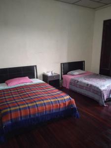 two beds sitting in a room with wooden floors at Residencias MARGARITA in Manizales