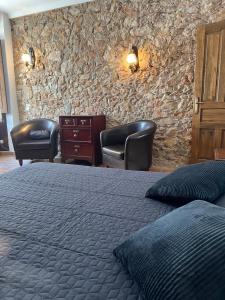1 dormitorio con 1 cama, 2 sillas y pared de piedra en Apartamento DEL SOL, Aire Acondicionado Free, en L'Escala