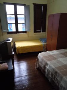 a room with two beds and a tv and two windows at Residencias MARGARITA in Manizales