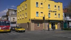 un edificio amarillo en una calle de la ciudad con un autobús en Hotel Astur, en Guadalajara