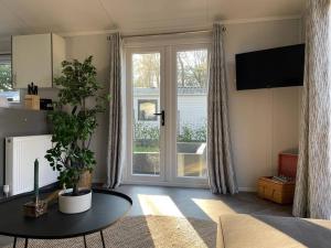 een woonkamer met een tafel en een groot raam bij Luxe chalet (gloednieuw!) in Hoenderloo in Hoenderloo