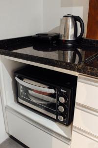 a microwave oven sitting on top of a kitchen counter at Pousada Refúgio do Vale - Praia do Rosa in Praia do Rosa