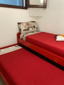 a bedroom with two beds with red sheets and a window at al Sulcis 35 in Teulada