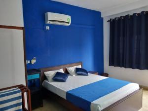 a blue bedroom with a bed with a blue wall at The Madampa Sea Side Lodge in Ambalangoda