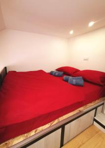 Un dormitorio con una gran cama roja con almohadas azules en Dunja Apartmans, en Belgrado